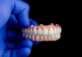 Dentist holding implant dentures in Irving