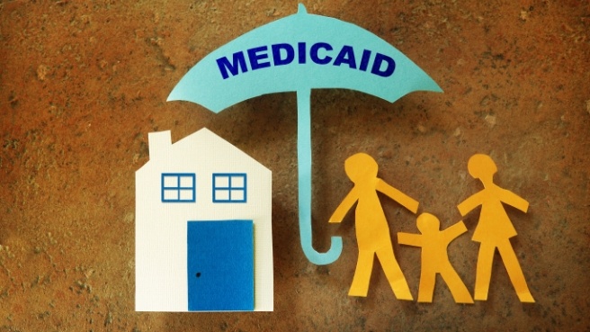 Paper cutouts of family of three under umbrella that reads Medicaid