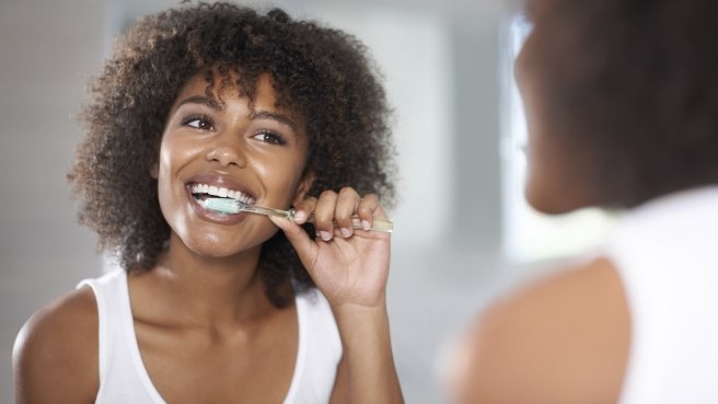 Woman smiling while brushing her teeth