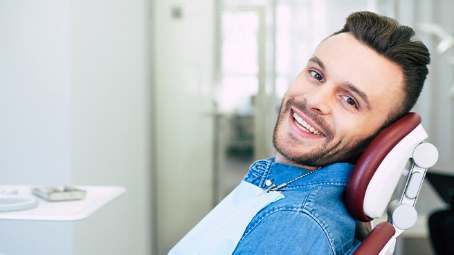 a smiling man sitting in a dental chair
