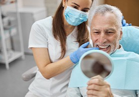 a man sitting in a dental chair looking into a handheld mirror