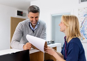 a woman in scrubs handing a man paperwork over a counter