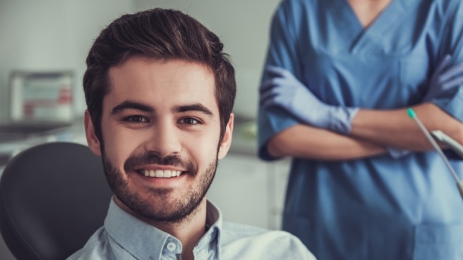 Young man with short beard smiling in dental chair