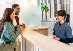patients speaking with a front desk staff member at a dental office