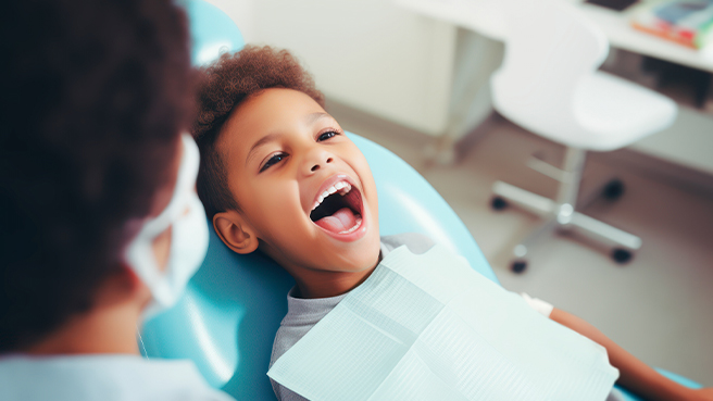 Child opening their mouth wide in dental chair
