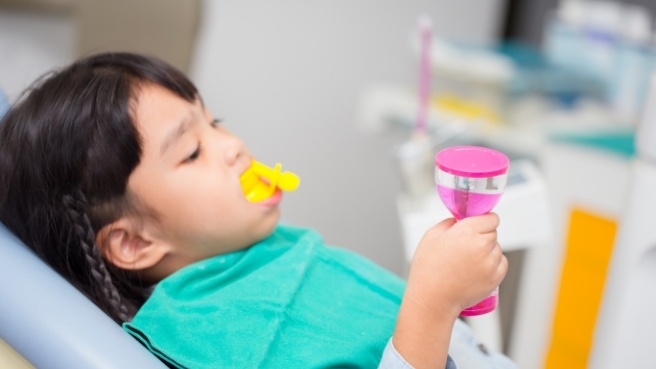 Young girl in dental chair with fluoride trays over her teeth