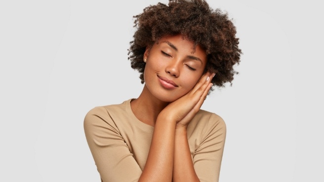 Woman making pillow shape with hands and pretending to sleep