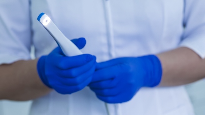 Dentist holding thin white intraoral camera