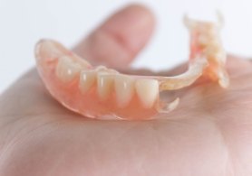 Hand holding a partial denture in Irving