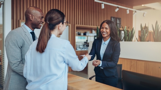 Woman handing payment card to dental team member