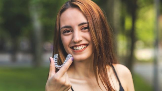 Smiling woman holding Invisalign tray