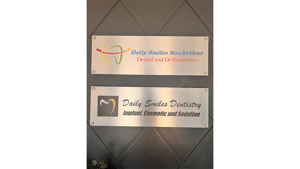 Two small metal plates with logos for Daily Smiles MacArthur Dental and Orthodontics