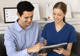 a dental assistant helping a patient fill out paperwork