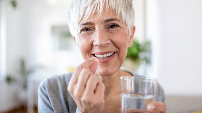 Woman holding pill and glass of water