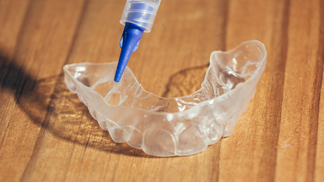 Close up of person putting gel into teeth whitening tray
