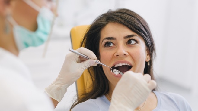 Woman looking at her dentist while he examines her teeth