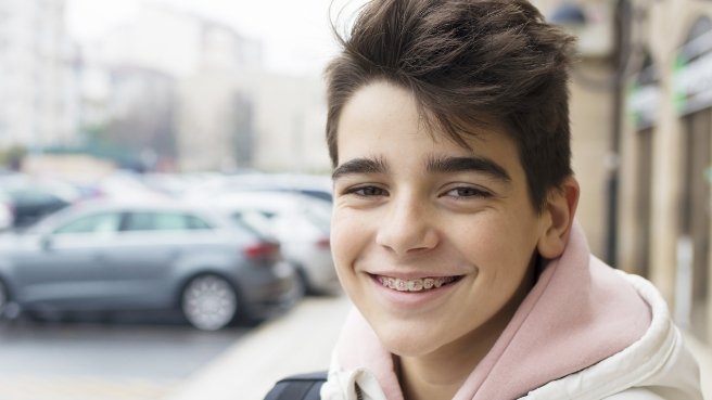 Teen boy on city sidewalk smiling with braces