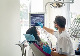 a dentist showing a patient an X-ray on a chairside monitor