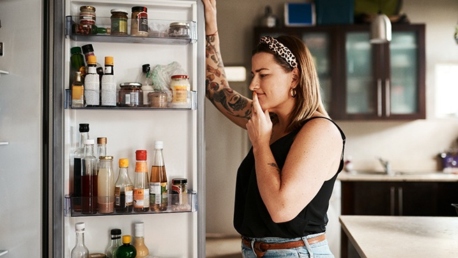 a woman looking  in her refrigerator