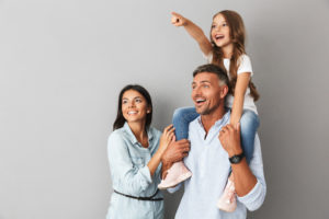 happy family with child on father's shoulders, gray background