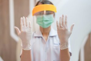 an emergency dentist in Irving wearing a mask, gloves, and a face shield