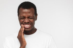 person holding their mouth due to a painful toothache in Irving