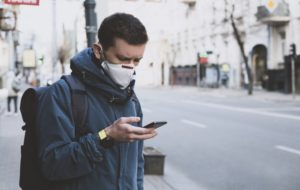 person with a mask on, calling their dentist to ask how they're accommodating at-risk patients in Irving