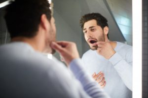 person examining their teeth in a bathroom mirror