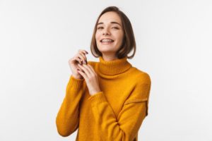 a person with braces smiling and wearing a yellow turtleneck sweater