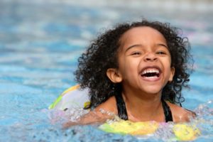 a child swimming in a pool and smiling