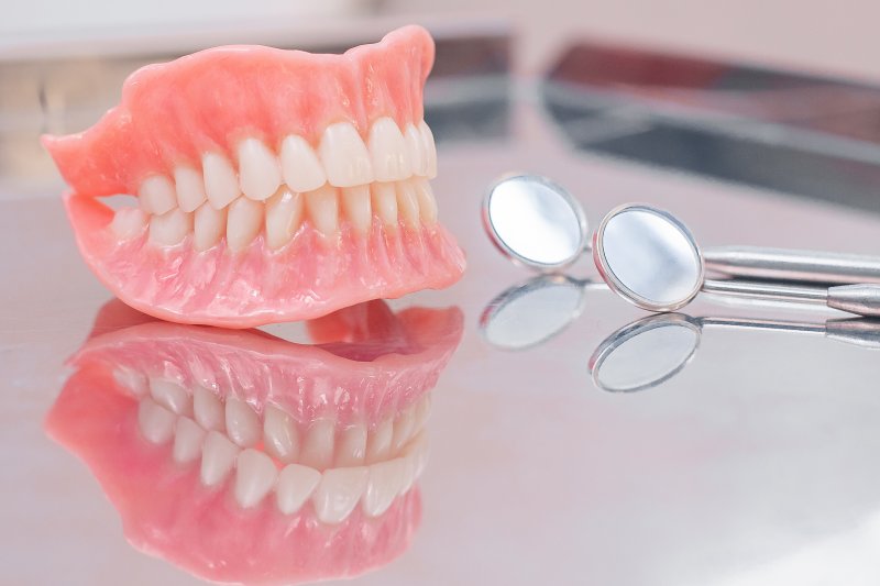 Dentures sitting next to dentist tools