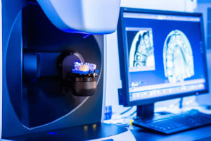 advanced dental technology crafting dental implants next to a computer monitor