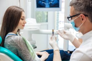 a dentist showing a patient how a dental implant works