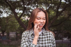 a person with braces holding their cheek in pain