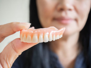 a woman holding dentures