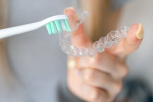 a person cleaning their Invisalign aligners