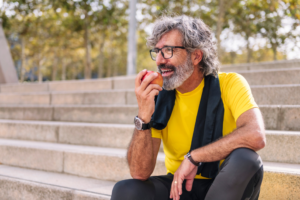 a man sitting on steps outdoors eating an apple