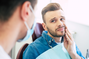 a person holding their mouth looking uncomfortable